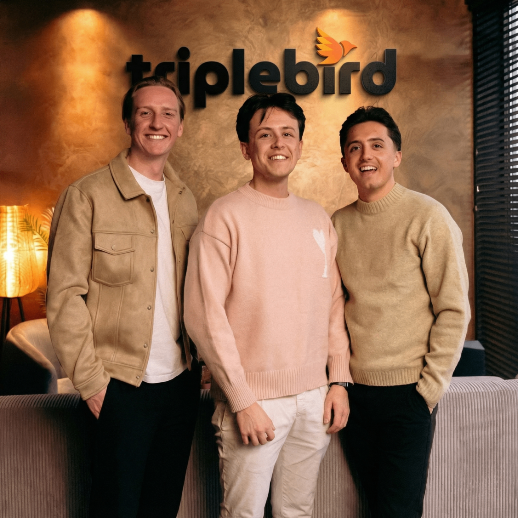 Loy, Floris en Sem van Triplebird staan voor een muur met het oranje Triplebird logo